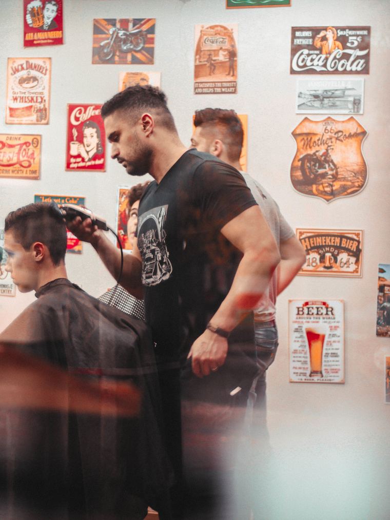 A barber leaning in to finish the line above a client's ear
